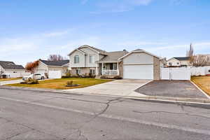 Tri-level home with a front lawn, covered porch, and a garage