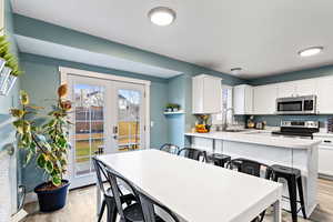 Kitchen featuring a breakfast bar, white cabinetry, sink, and appliances with stainless steel finishes