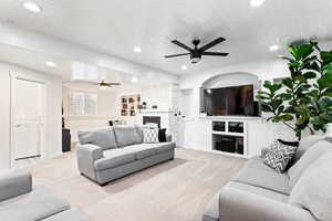 Living room featuring a fireplace, built in shelves, ceiling fan, and wood ceiling