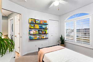 Carpeted bedroom with ceiling fan and a closet