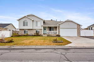 Split level home with a porch, a garage, and a front lawn