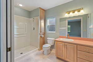 Bathroom featuring a shower, vanity, and toilet