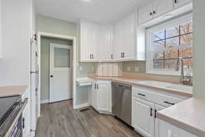 Kitchen with white cabinetry, sink, range with electric cooktop, stainless steel dishwasher, and white refrigerator