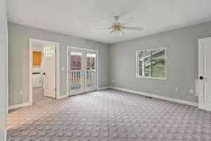 Carpeted empty room with ceiling fan and french doors