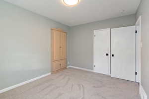 Unfurnished bedroom with a closet and light colored carpet