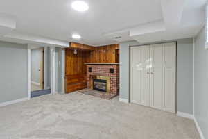 Unfurnished living room featuring wooden walls, a fireplace, and light carpet