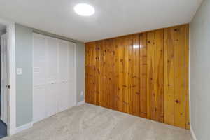 Unfurnished bedroom featuring carpet and wood walls