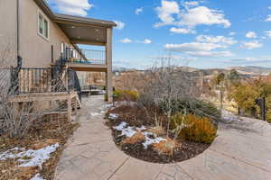 Yard covered in snow with a mountain view, a patio, and a balcony