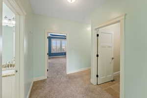 Hall with light colored carpet and sink