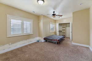 Carpeted bedroom with ceiling fan and a closet