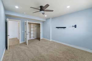 Unfurnished bedroom with ceiling fan, light carpet, and a closet