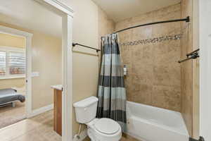 Full bathroom with tile patterned floors, shower / tub combo with curtain, vanity, and toilet