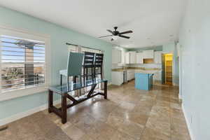 Kitchen with white cabinetry, a center island, ceiling fan, decorative backsplash, and a breakfast bar