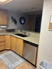 Kitchen featuring dishwasher, light tile patterned floors, and sink