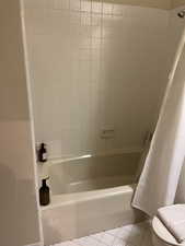 Bathroom with tile patterned floors and shower / tub combo with curtain