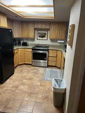 Kitchen with black refrigerator, light tile patterned flooring, and stainless steel electric range oven