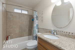 Full bathroom featuring vanity, shower / bath combination with curtain, tile walls, and toilet