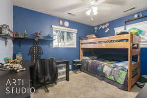 Carpeted bedroom with ceiling fan and a textured ceiling