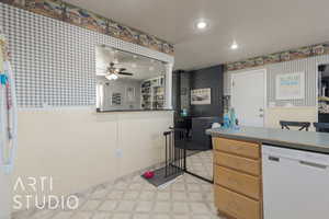 Kitchen featuring a textured ceiling, white dishwasher, ceiling fan, and wood walls