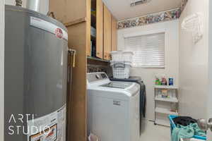 Washroom featuring cabinets, washing machine and dryer, and water heater