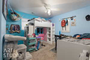 Carpeted bedroom featuring ceiling fan and a textured ceiling