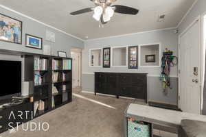 Living area with a textured ceiling, carpet floors, ceiling fan, and crown molding