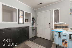 Tiled entrance foyer featuring crown molding