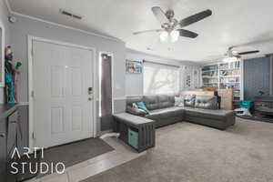 Living room featuring a wood stove, ceiling fan, light tile patterned floors, and a textured ceiling