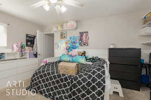 Bedroom with ceiling fan, carpet floors, and a textured ceiling