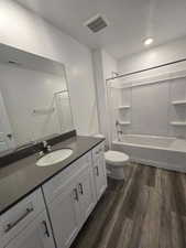 Full bathroom with hardwood / wood-style flooring, vanity, shower / bath combination, and a textured ceiling