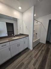 Bathroom with hardwood / wood-style flooring, vanity,  shower combination, and a textured ceiling