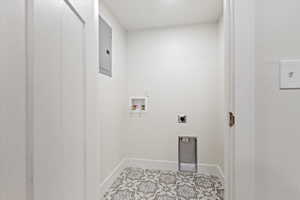 Clothes washing area featuring hookup for an electric dryer, light tile patterned flooring, electric panel, and washer hookup