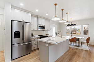 Kitchen with pendant lighting, sink, an island with sink, light stone counters, and stainless steel appliances