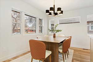 Dining room with light hardwood / wood-style flooring and a notable chandelier