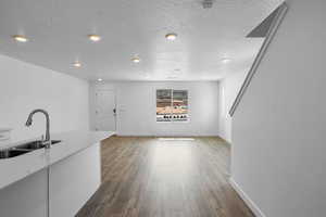 Unfurnished living room with a textured ceiling, dark hardwood / wood-style flooring, and sink