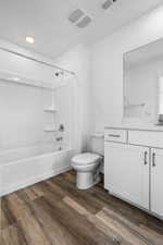 Full bathroom with bathing tub / shower combination, vanity, wood-type flooring, and toilet