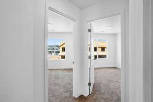 Hallway with dark colored carpet and a textured ceiling