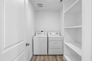 Clothes washing area with hardwood / wood-style flooring and washing machine and dryer