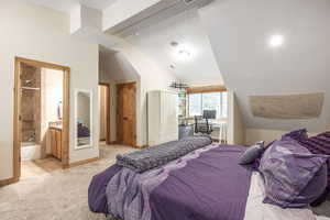 Carpeted bedroom featuring connected bathroom and vaulted ceiling