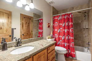 Full bathroom featuring shower / bath combo with shower curtain, vanity, and toilet