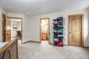 Carpeted bedroom featuring ensuite bath and a textured ceiling