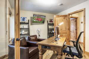 Office space with a textured ceiling and light hardwood / wood-style flooring