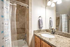 Bathroom featuring vanity and shower / bathtub combination with curtain