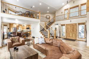 Living room with high vaulted ceiling and light wood-type flooring