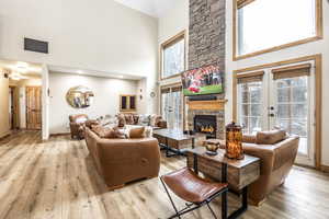 Living room with light wood-type flooring, a towering ceiling, and french doors