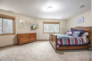 Bedroom with light colored carpet and a textured ceiling