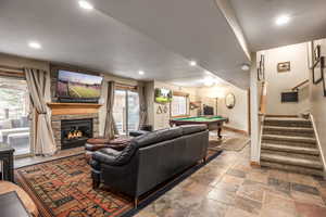 Living room featuring a stone fireplace and billiards