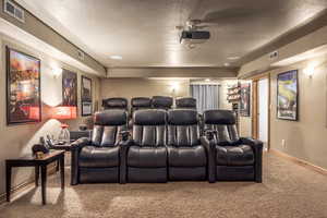 Home theater with a textured ceiling and carpet floors