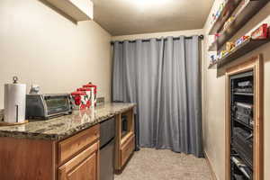 Kitchen featuring light carpet, a textured ceiling, and dark stone countertops