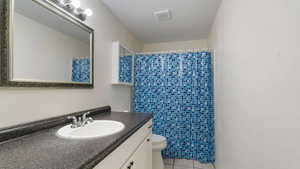 Bathroom with curtained shower, tile patterned flooring, vanity, and toilet